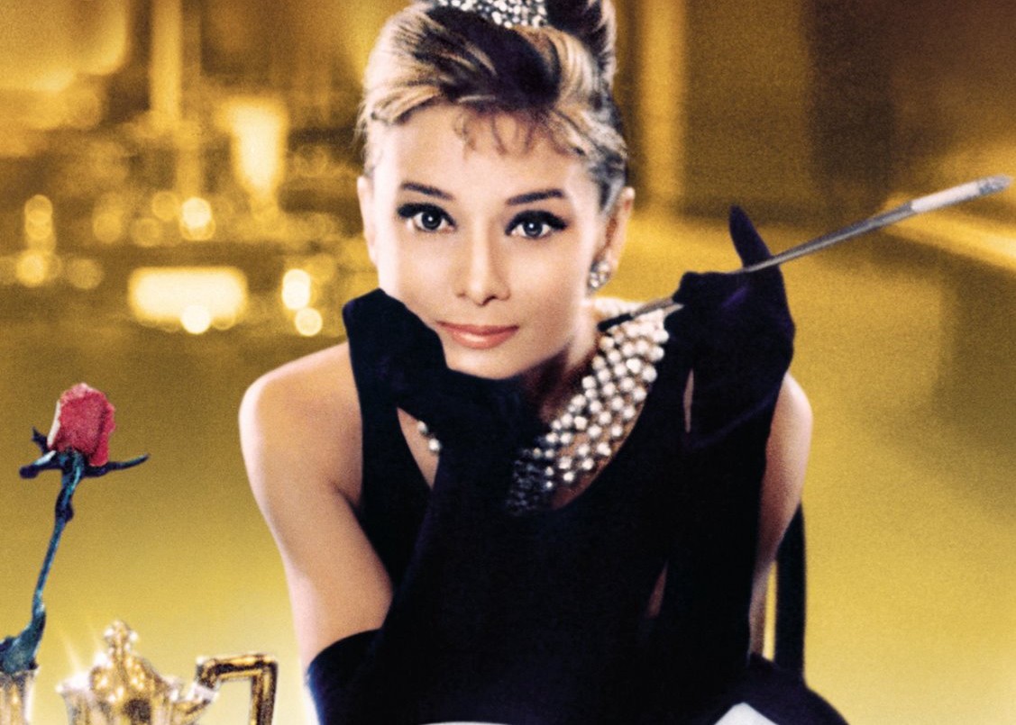 Audrey Hepburn as Holly Golightly in a black dress and pearl necklace