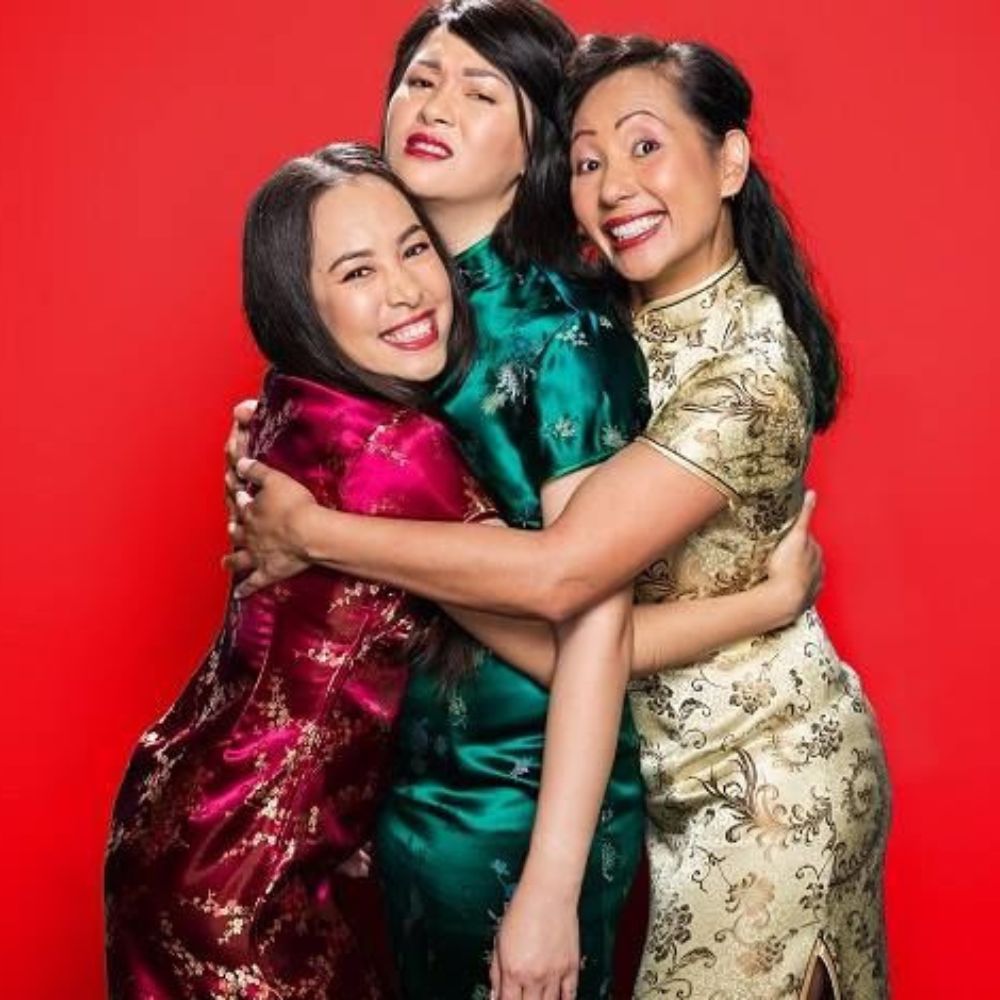 3 Asian women in qipao hugging and smiling