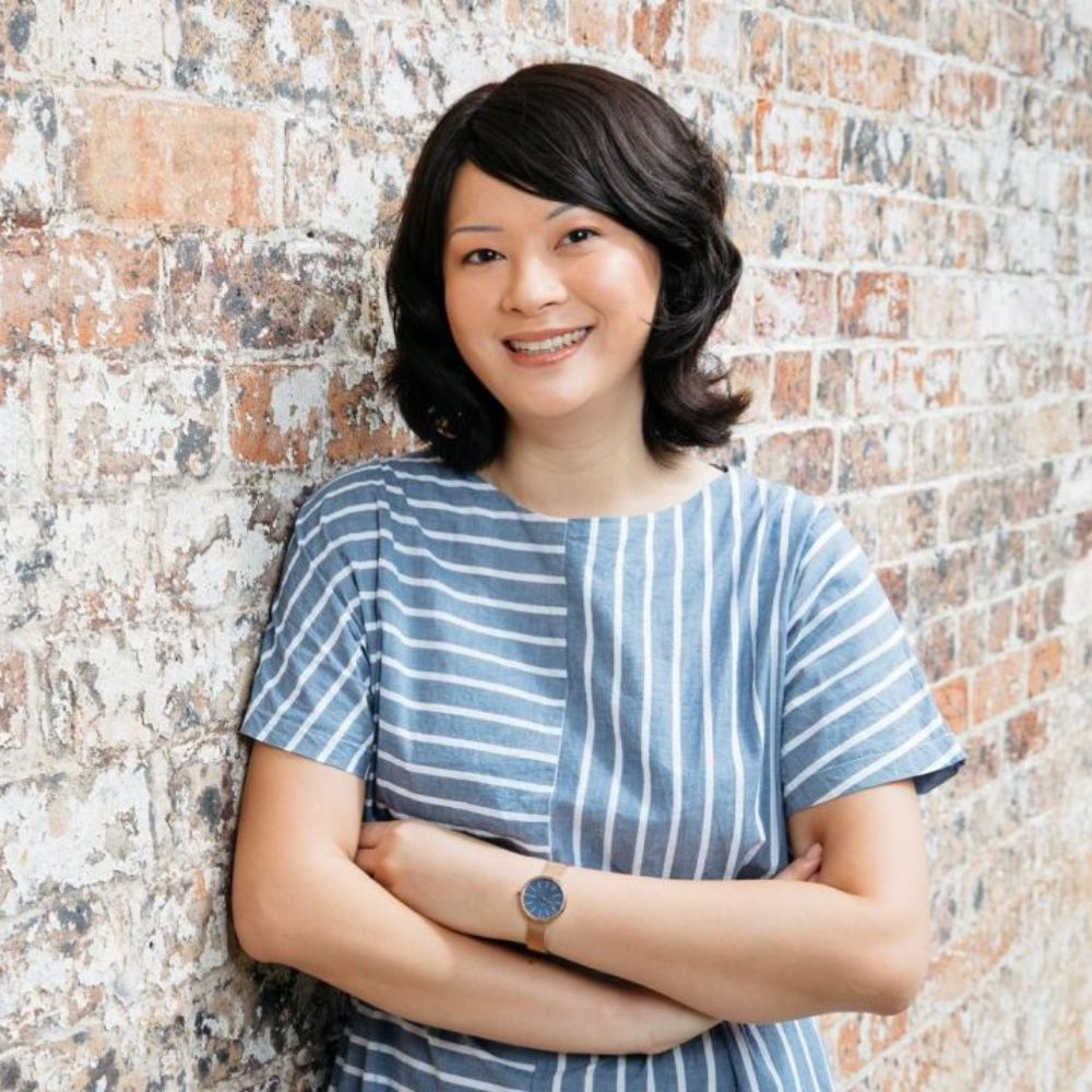 Asian woman smiling leaning against brick wall