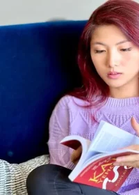 Clara Yehonala sitting with book in purple sweater